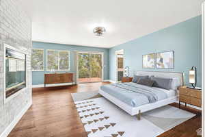 Bedroom featuring hardwood / wood-style flooring, access to exterior, a large fireplace, and connected bathroom