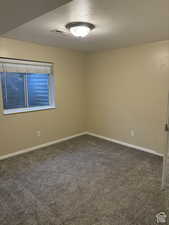 Unfurnished room with a textured ceiling and dark carpet