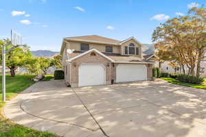 Traditional-style home with a mountain view, concrete driveway, brick siding, a shingled roof, and stucco siding