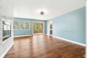 Unfurnished living room with a glass covered fireplace and dark wood finished floors