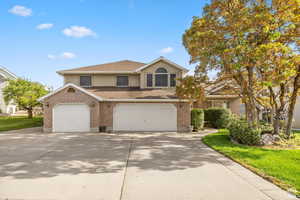 Traditional-style home with driveway, a shingled roof, a garage, and brick siding