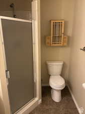 Full bath featuring a shower stall and dark tile patterned flooring