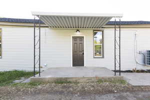 Property entrance featuring a patio and roof with shingles
