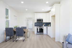 Kitchen featuring light countertops, white cabinets, stainless steel appliances, light wood-type flooring, and recessed lighting