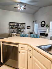 Kitchen with stainless steel dishwasher, open floor plan, light countertops, lofted ceiling, and ceiling fan