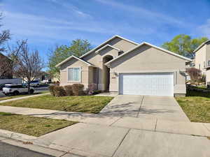 Ranch-style house featuring a front lawn, a garage, concrete driveway, and stucco siding