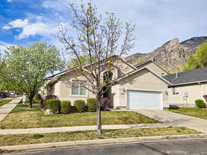 View of front of house featuring concrete driveway, stucco siding, an attached garage, and a front lawn