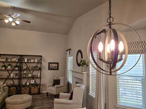 Sitting room with vaulted ceiling, a chandelier, a ceiling fan, and a fireplace