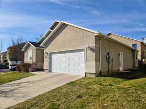 View of home's exterior featuring stucco siding, a garage, driveway, and a lawn