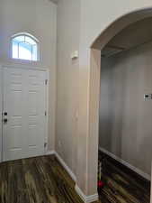 Entryway with dark wood finished floors, a high ceiling, and arched walkways