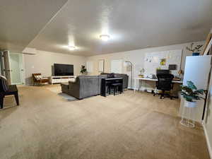 Living room featuring an office area, a textured ceiling, and light carpet