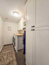 Laundry area with a textured ceiling, washing machine and dryer, and cabinet space