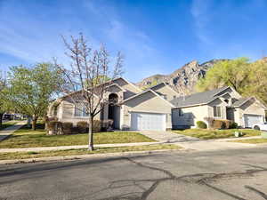 Ranch-style home with a garage, driveway, a front yard, a residential view, and a mountain view
