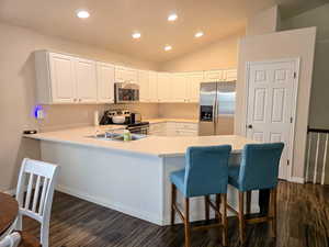 Kitchen with a kitchen breakfast bar, light countertops, stainless steel appliances, white cabinetry, and recessed lighting