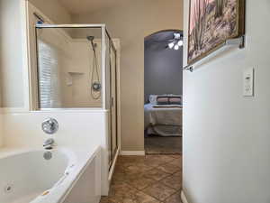 Ensuite bathroom with ceiling fan, a shower stall, and a garden tub