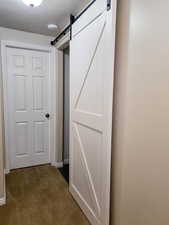 Hallway featuring a barn door, dark carpet, and a textured ceiling