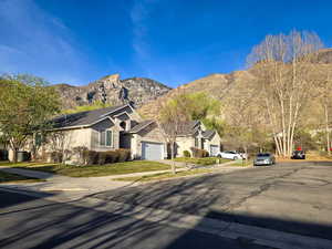 View of front of home with stucco siding, a garage, a mountain view, driveway, and a front lawn