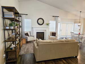 Living room with lofted ceiling, a glass covered fireplace, and dark wood-style flooring