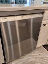 Kitchen view of dishwasher and white cabinets