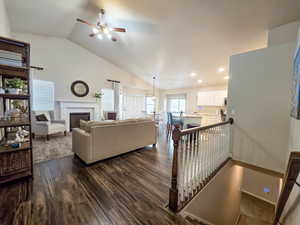 Living area featuring a glass covered fireplace, lofted ceiling, ceiling fan, dark wood-style flooring, and recessed lighting
