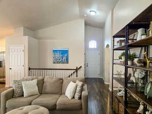 Living room featuring vaulted ceiling and dark wood-type flooring