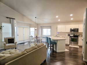 Living area with dark wood-style flooring, lofted ceiling, and hanging lights