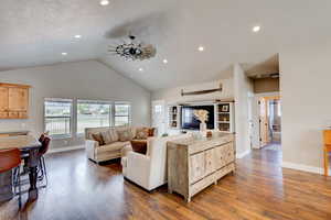 Living area with dark wood-type flooring, a ceiling fan, recessed lighting, and a high ceiling
