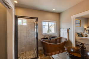 Full bathroom with ensuite bath, a shower stall, wood finished floors, recessed lighting, and a freestanding bath