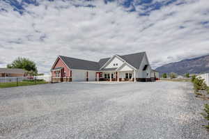 View of front of home featuring stone siding, a mountain view, a porch, gravel driveway, and an attached garage