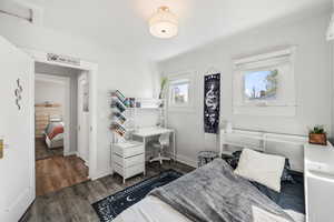Bedroom with dark wood finished floors and an office area