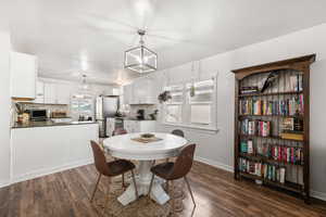 Dining space with dark wood-style flooring and hanging lights