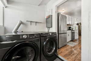 Laundry area featuring washing machine and dryer, dark wood-style floors, and electric panel