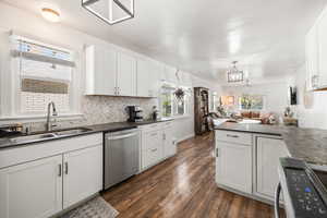 Kitchen featuring black range with electric cooktop, white cabinetry, open floor plan, stainless steel dishwasher, and dark wood-style flooring