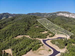 Aerial view of property and surrounding area featuring a mountain backdrop and property parcel outlined