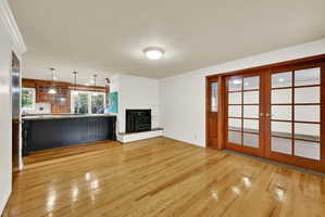 Unfurnished living room with french doors, light wood-style floors, ornamental molding, a textured ceiling, and a wood stove