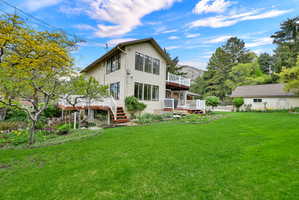 Rear view of house featuring a yard and a wooden deck