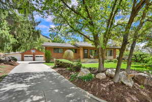 Single story home featuring an outdoor structure, brick siding, a detached garage, covered porch, and a front yard