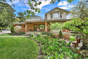 View of front of house featuring covered porch, brick siding, and a front lawn