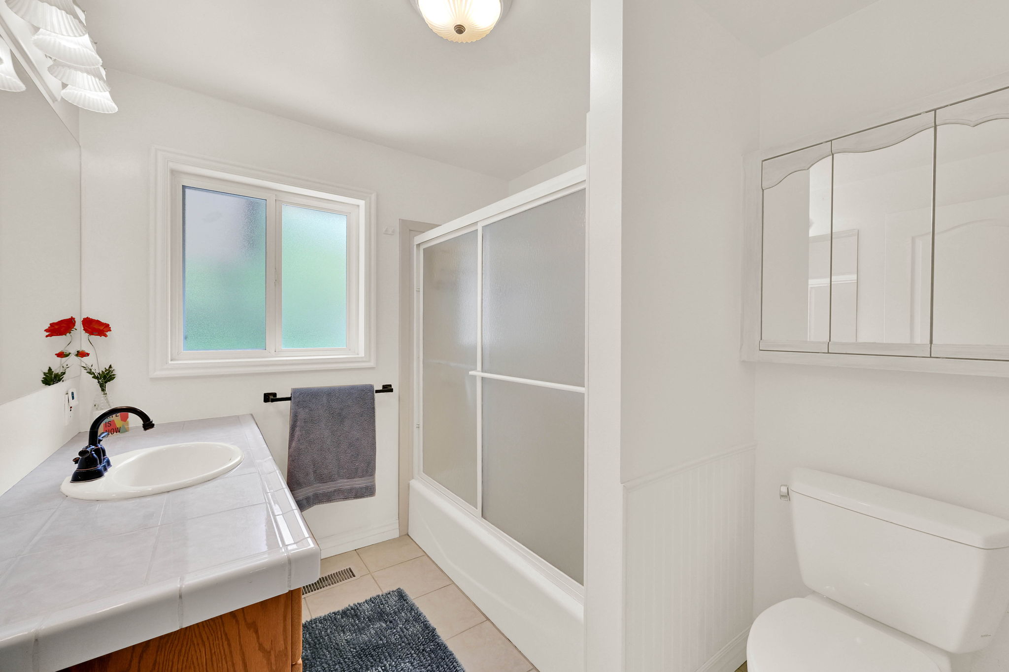 Bathroom featuring vanity, light tile patterned floors, and bath / shower combo with glass door