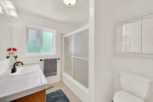 Bathroom featuring vanity, light tile patterned floors, and bath / shower combo with glass door