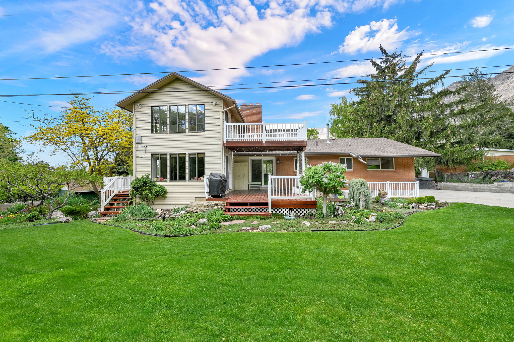 Back of property featuring a wooden deck, a yard, a chimney, and brick siding