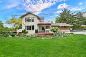 Back of property featuring a wooden deck, a yard, a chimney, and brick siding