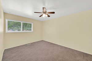 Spare room with dark colored carpet and a ceiling fan