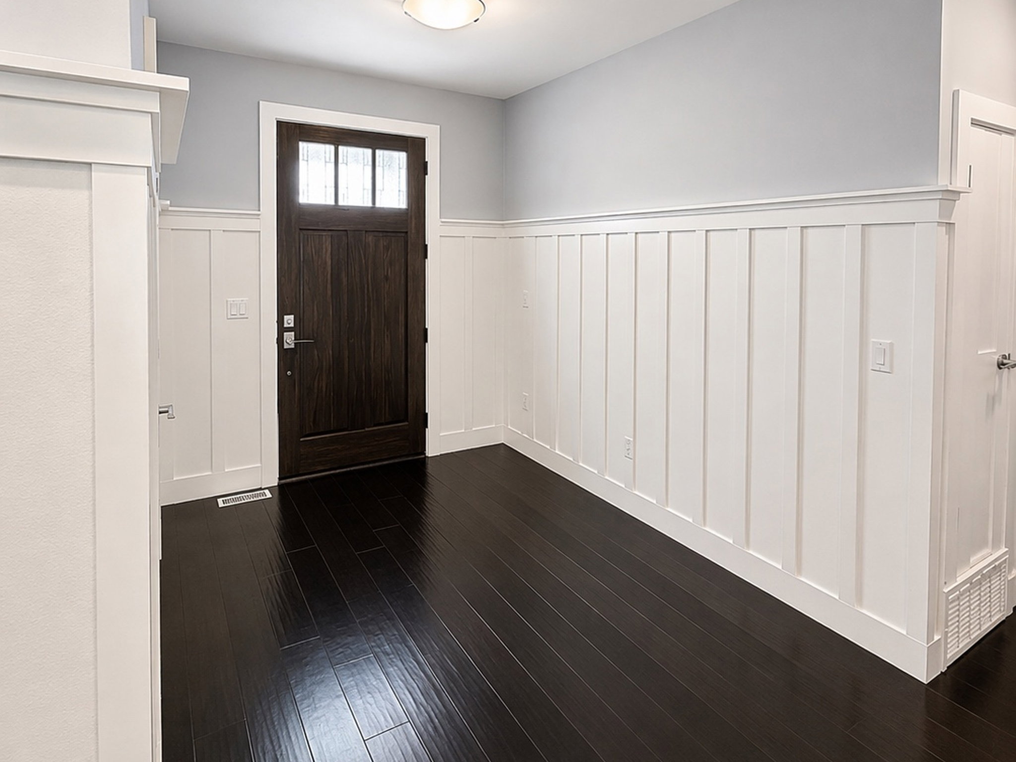 Foyer featuring a wainscoted wall, dark wood-style floors, and a decorative wall