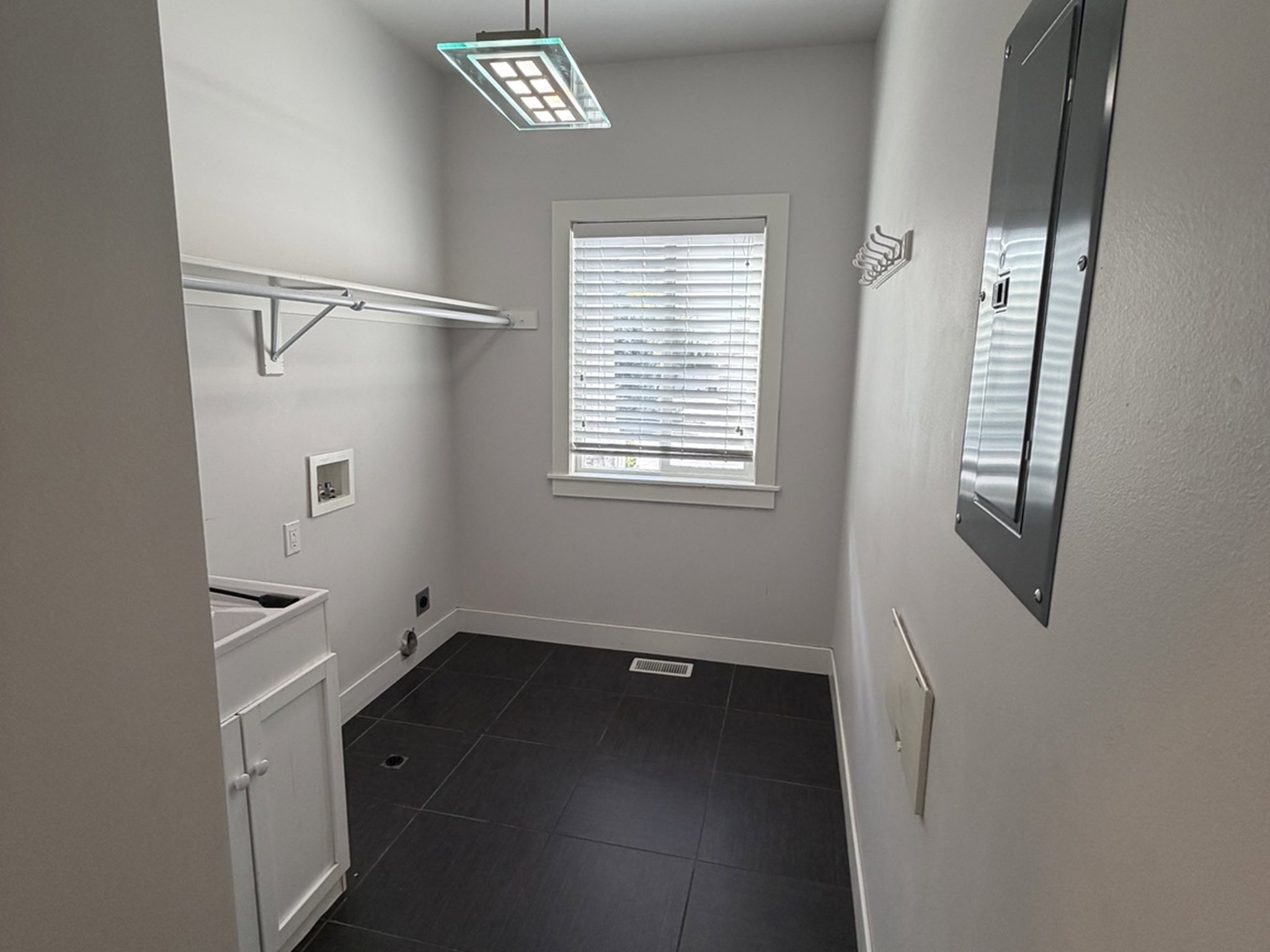Laundry room with hookup for a washing machine and dark tile patterned flooring