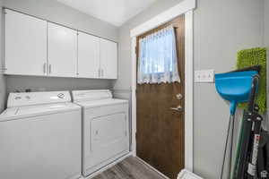 Laundry area with dark wood-style floors, washer and clothes dryer, and cabinet space