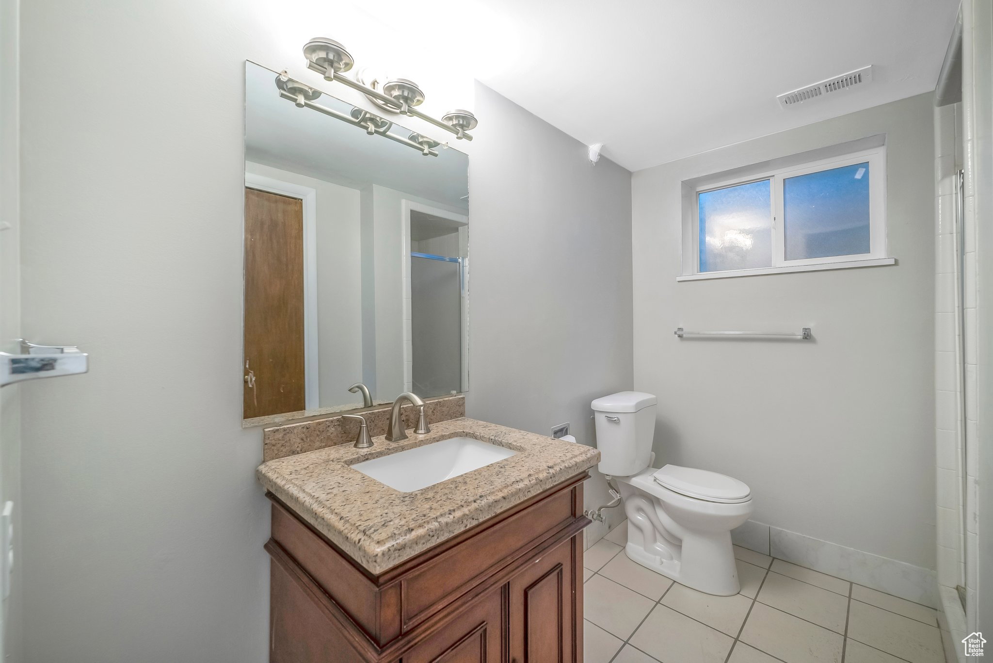 Full bath with vanity, light tile patterned floors, and a shower