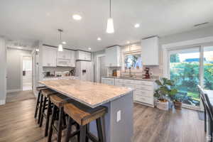Kitchen with a breakfast bar area, light stone countertops, dark wood-style floors, and white appliances