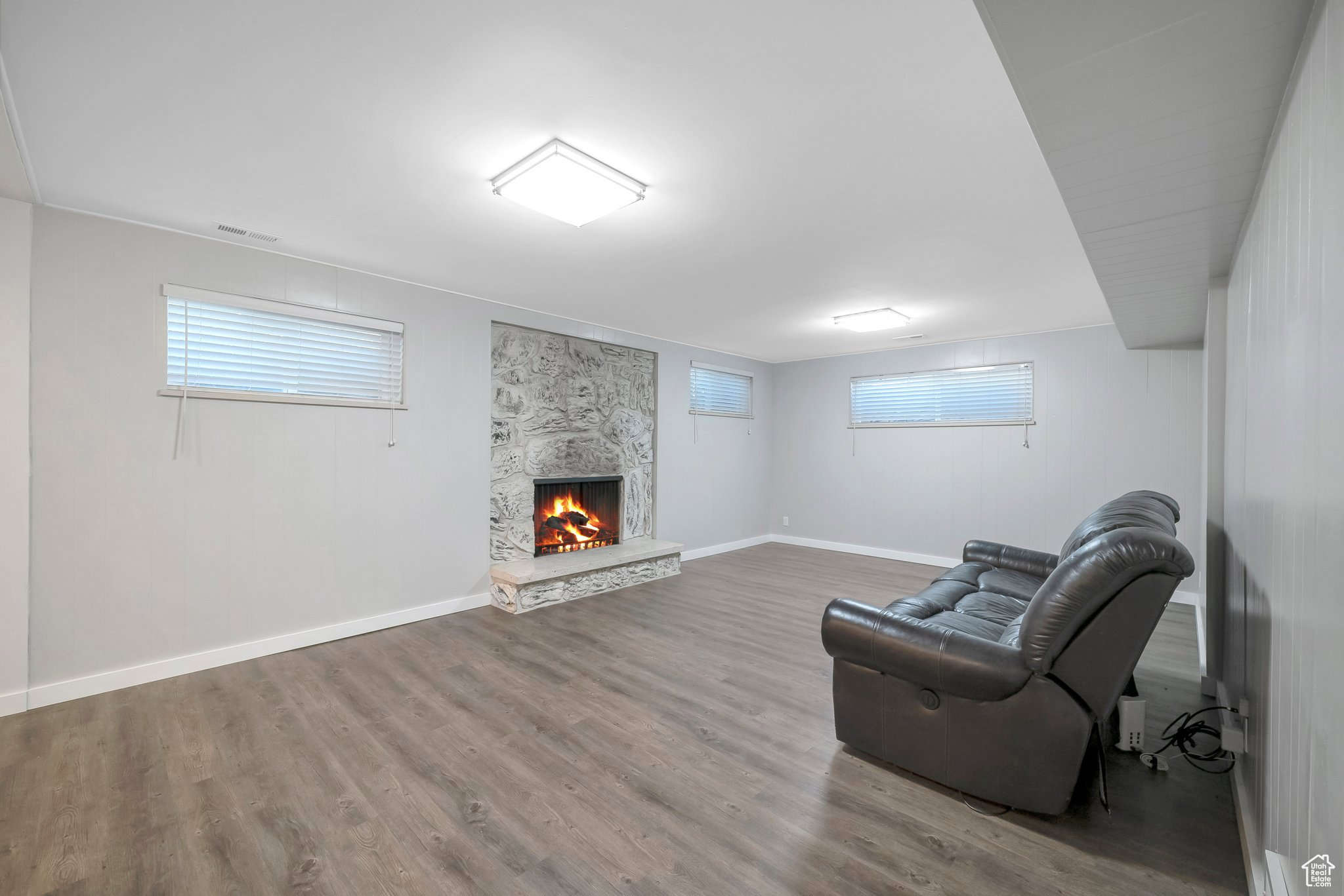 Unfurnished room with a stone fireplace and wood finished floors
