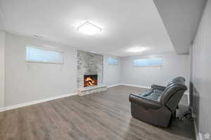 Unfurnished room with a stone fireplace and wood finished floors